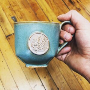 A turquoise mug with a white emblem.