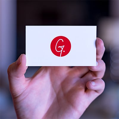 A hand holding a white business card with the Gravity Group logo on it.